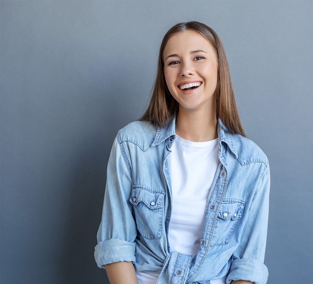 Person in Jeansjacke und weißem Hemd vor grauem Hintergrund