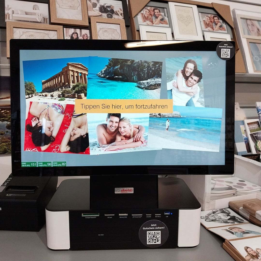 Bildschirm eines Fotokiosks, der Reisebilder über einem Drucker anzeigt